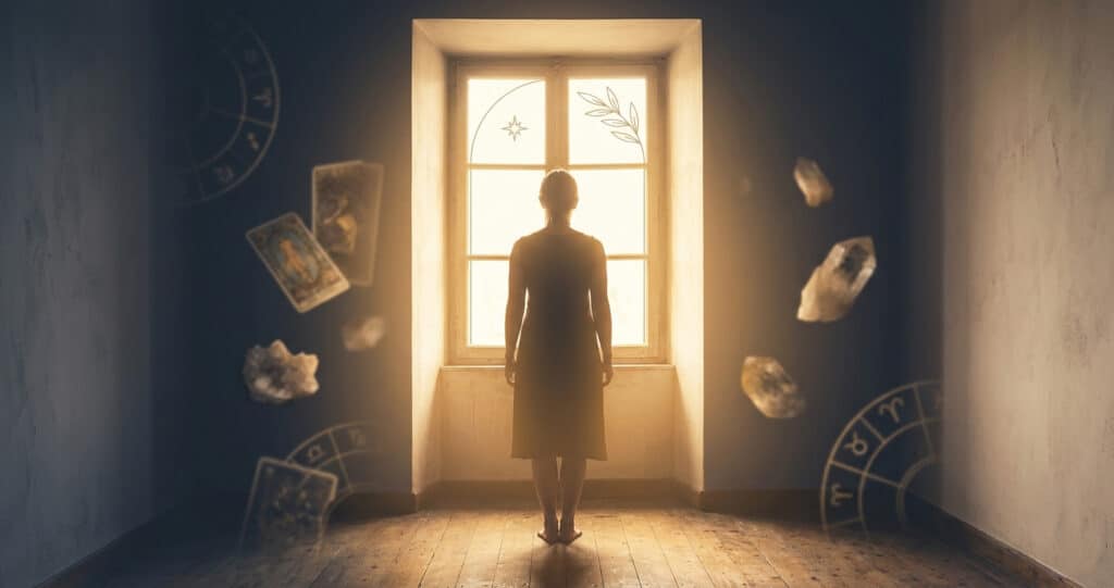 Femme de dos face à une fenêtre lumineuse, silhouette dans la pénombre — témoignage New Age et conversion spirituelle