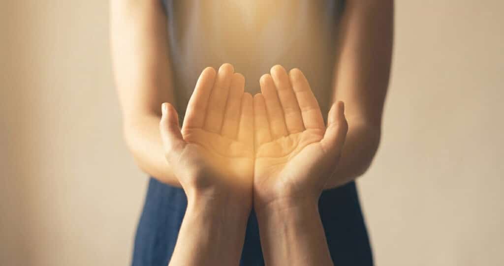 Mains ouvertes baignées d'une lumière dorée douce — symbole des dons spirituels réels dans le New Age