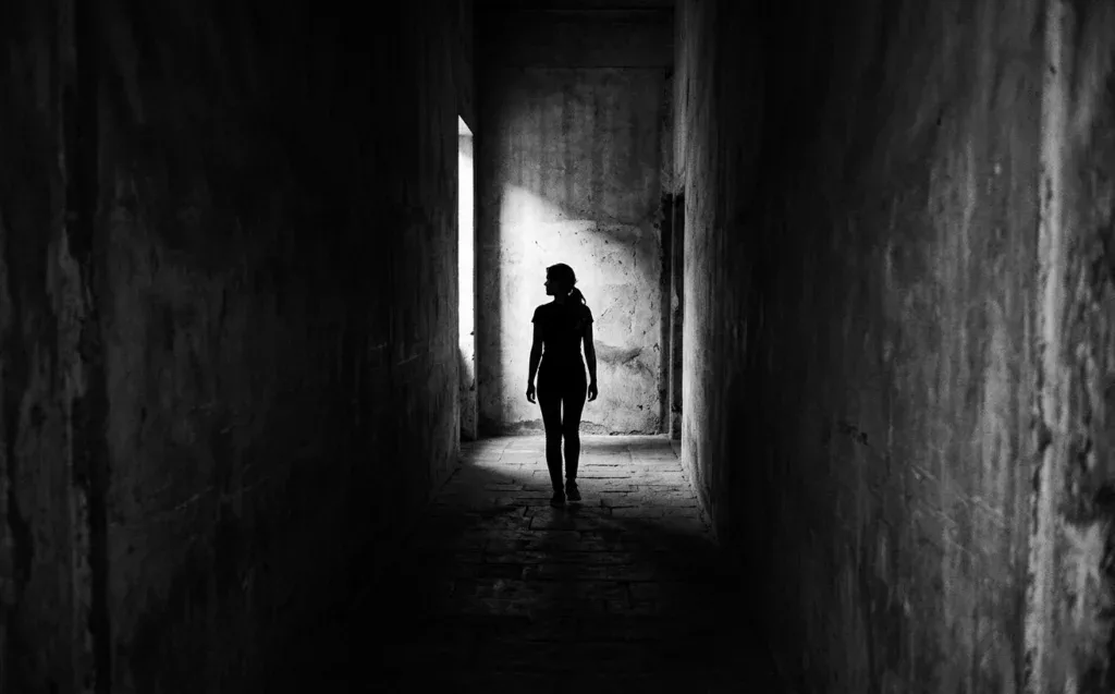 Silhouette seule dans un couloir sombre, représentant la rancœur qui emprisonne — pardon chrétien